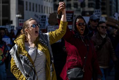 Felicia Yauch, left, holds hands and shouts with her friend Terrisa Scott, both of Chicago’s Andersonville neighborhood, during a women’s day march on East Wacker Drive in Chicago Sunday, March 8, 2026.