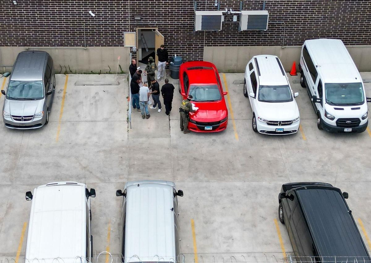 Detainees put items into clear plastic bags given to them by masked federal agents near an exterior door at the U.S. Immigration and Customs Enforcement holding facility in Broadview on Oct. 13, 2025.
